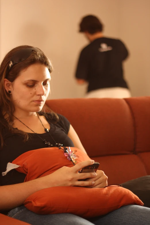 a woman sitting on a couch using her cell phone