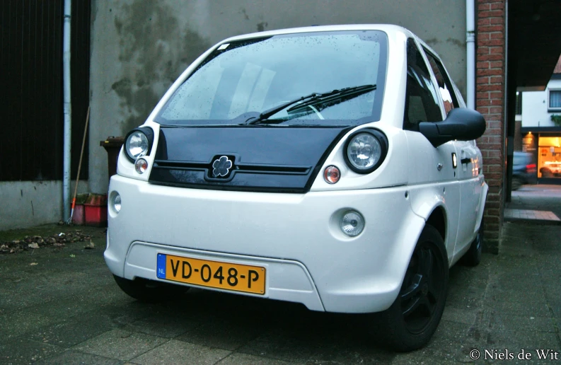 a close up of a white small car parked on the street