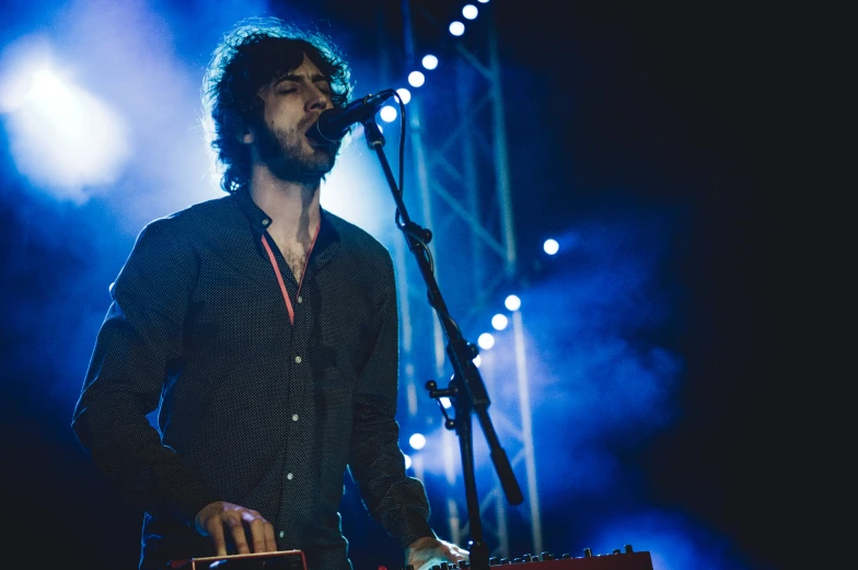 a male with a microphone and a guitar on stage