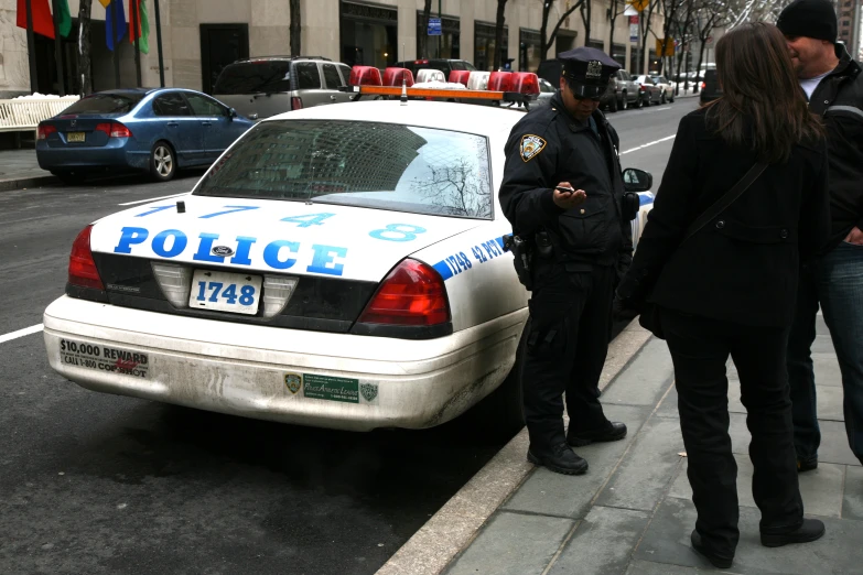 two police officers standing next to the back of a patrol car