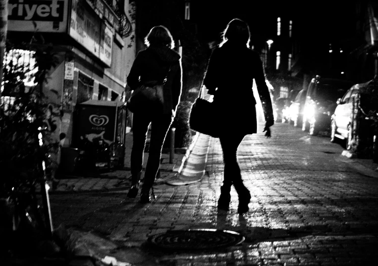 two girls walking down a sidewalk at night