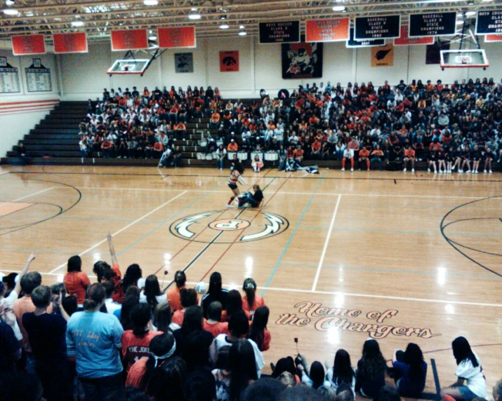 a crowd of people in a gym watching a basketball game