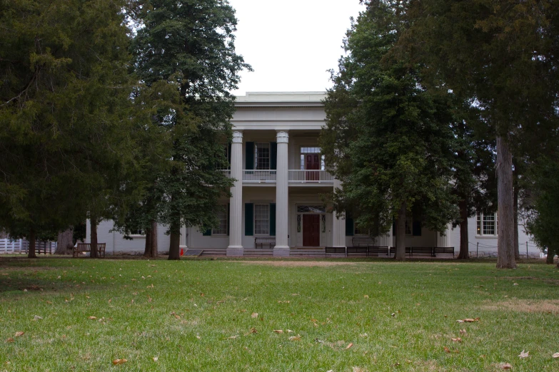 a big house with tall white pillars behind some trees