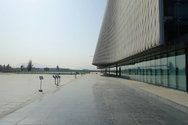 a large modern building on the edge of a large empty sidewalk