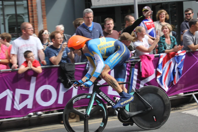 a man wearing an orange helmet riding a bike in front of a large group