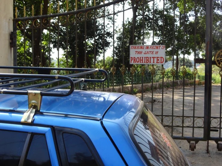 a blue car parked in front of a gate