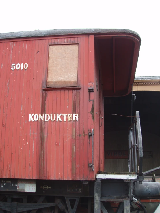 old train car from 1950 sits next to an old building