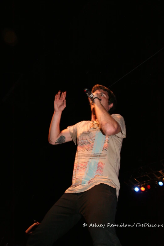 a man in black pants and a t - shirt holding a microphone up