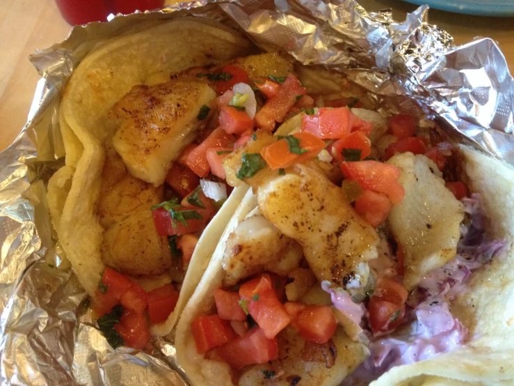 tacos are sitting on tin foil at a restaurant