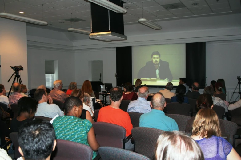 a group of people watching a lecture on a projector screen