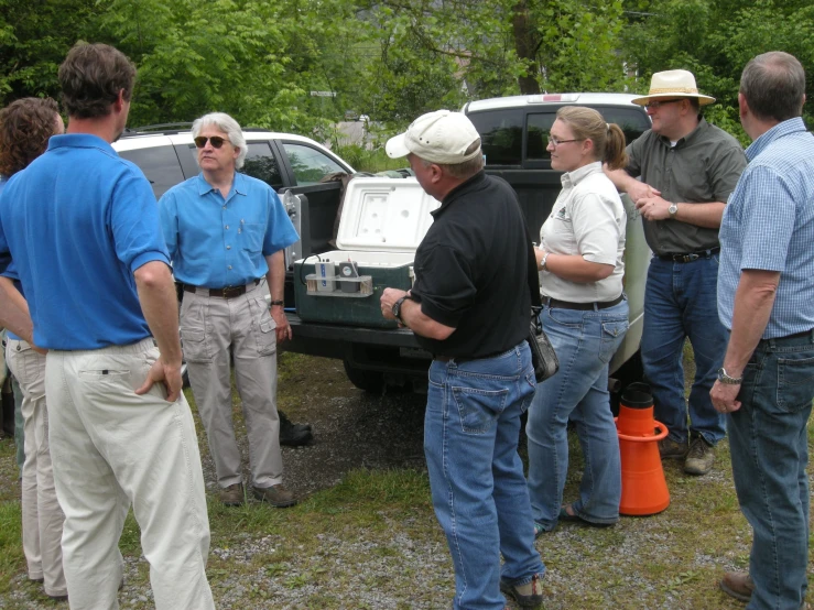 several men and women talking next to a black truck