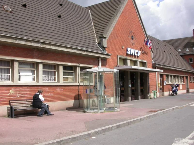 a man is sitting on a bench outside of a store