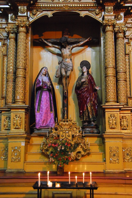 a wooden sculpture of jesus and mary in a church with candles