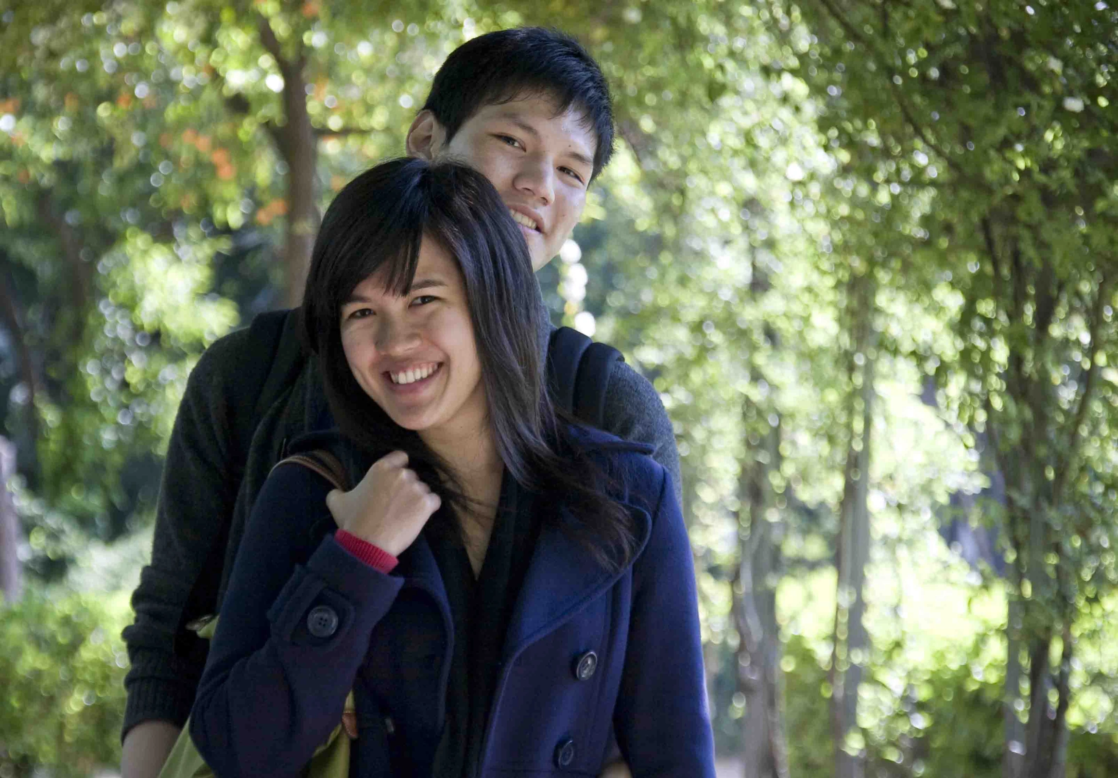 a couple smiles as they walk through the forest