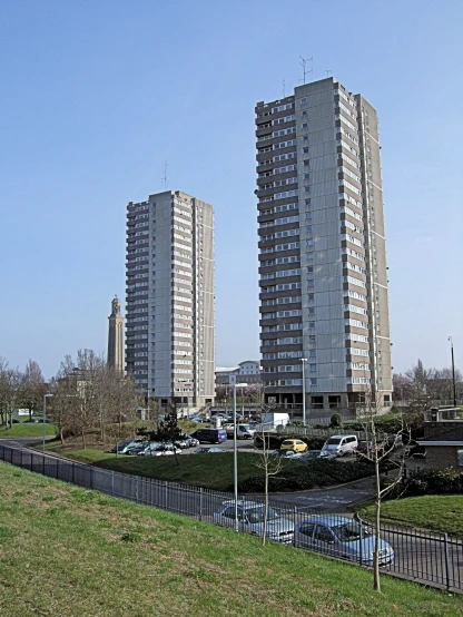 two tall buildings in the background with grass and trees