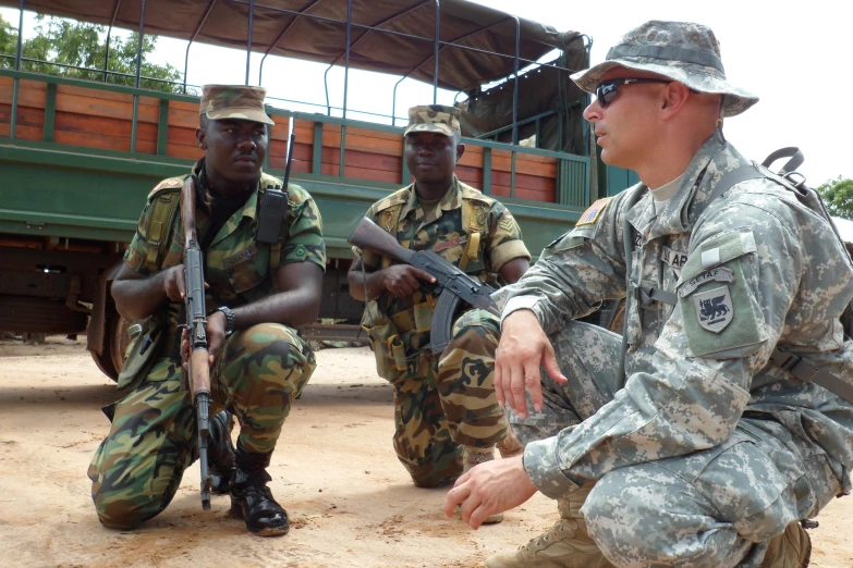 two soldiers hold rifles, while another man in fatigues stands near by