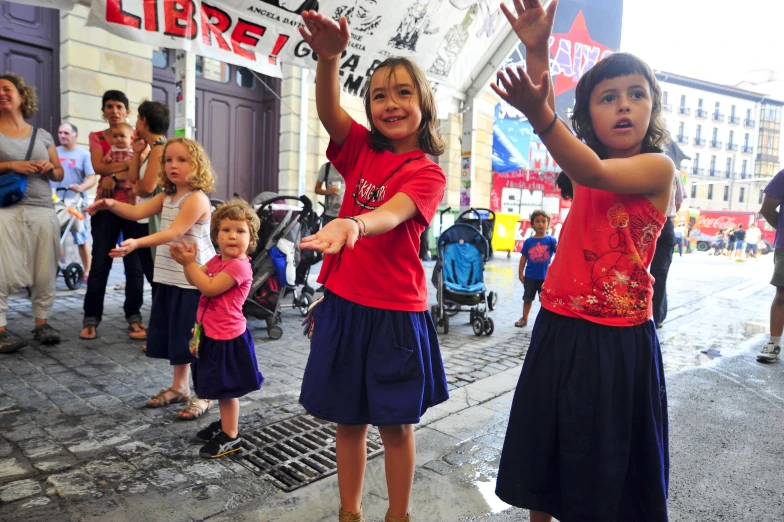 s in red shirts and skirts standing on the sidewalk