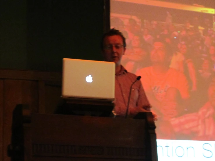 a person standing in front of a podium with an apple computer