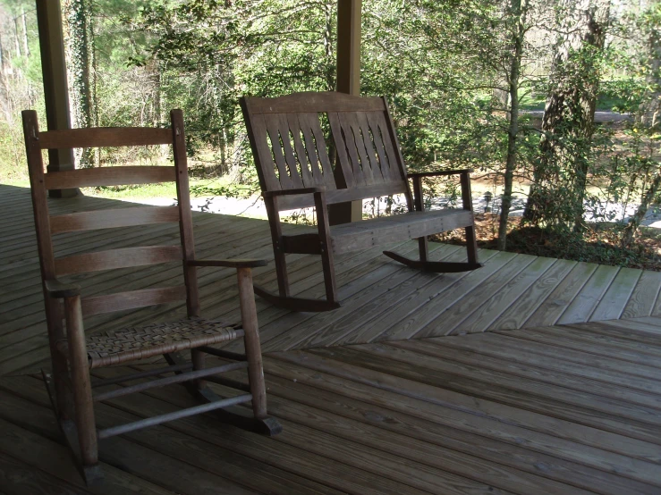 two rocking chairs and a rug are sitting on the wooden deck