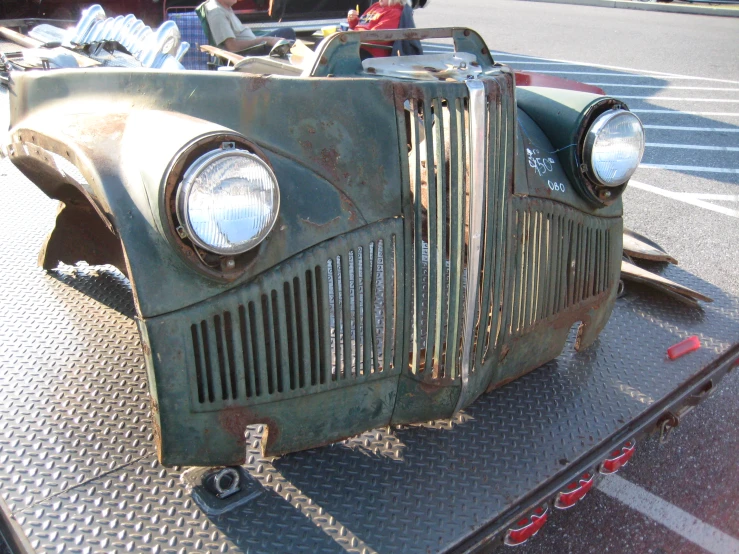 an old classic car sitting in the back of a flat bed