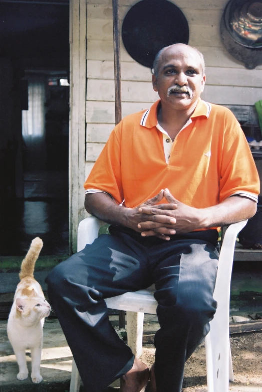 a man sitting down next to a white cat