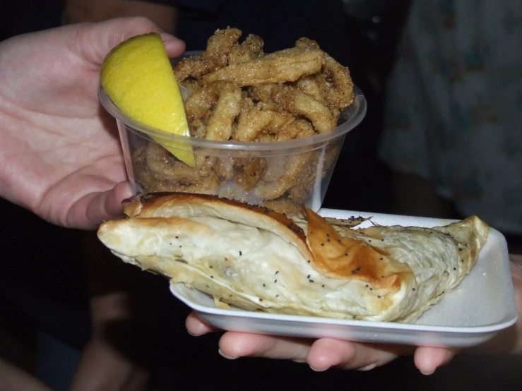 a close up of a person holding a small container of food