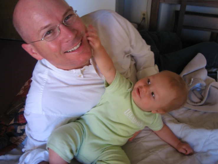 a man smiles with his baby on his lap