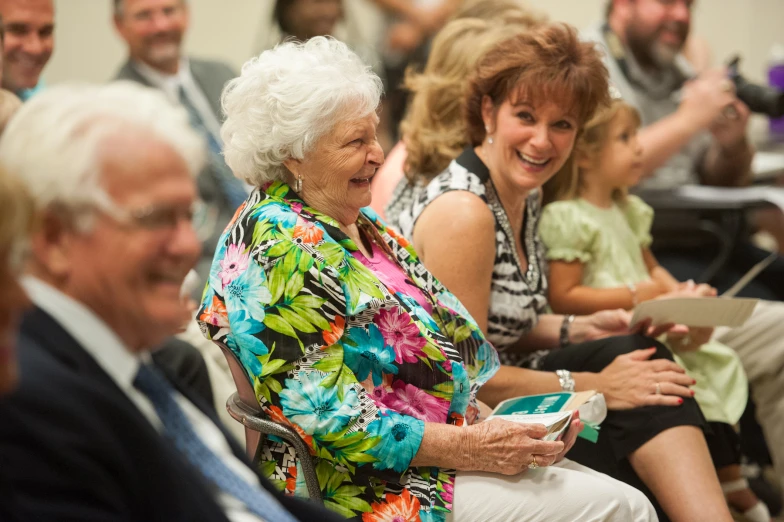 older woman laughing in front of a crowd of people