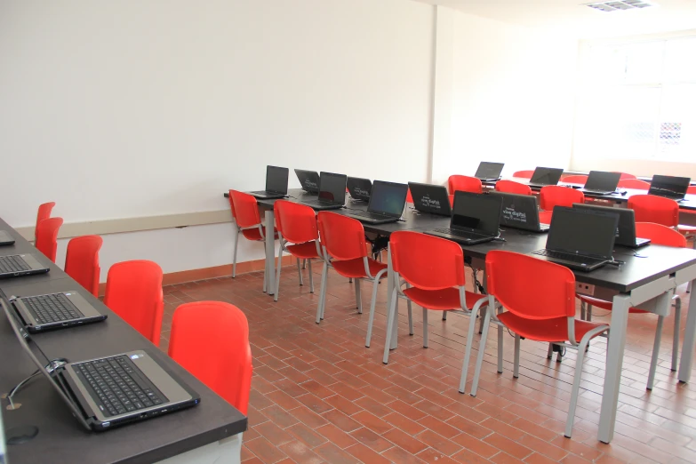 a computer room with rows of red chairs and lap tops