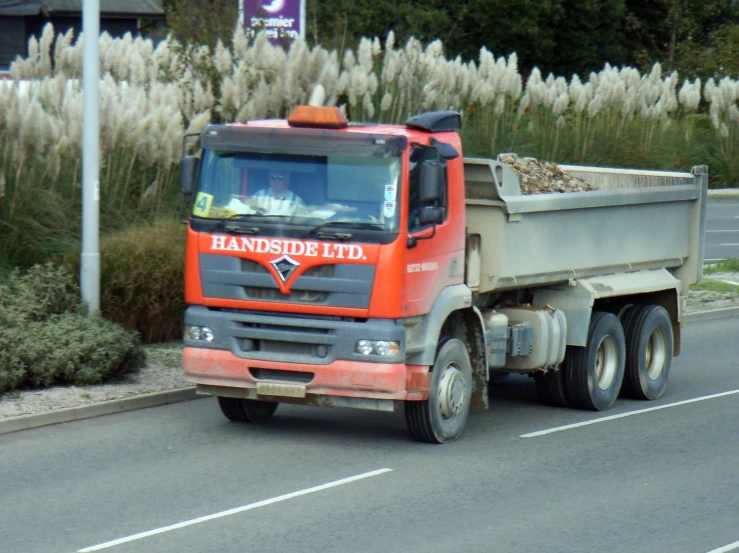 a truck traveling down the road near some flowers