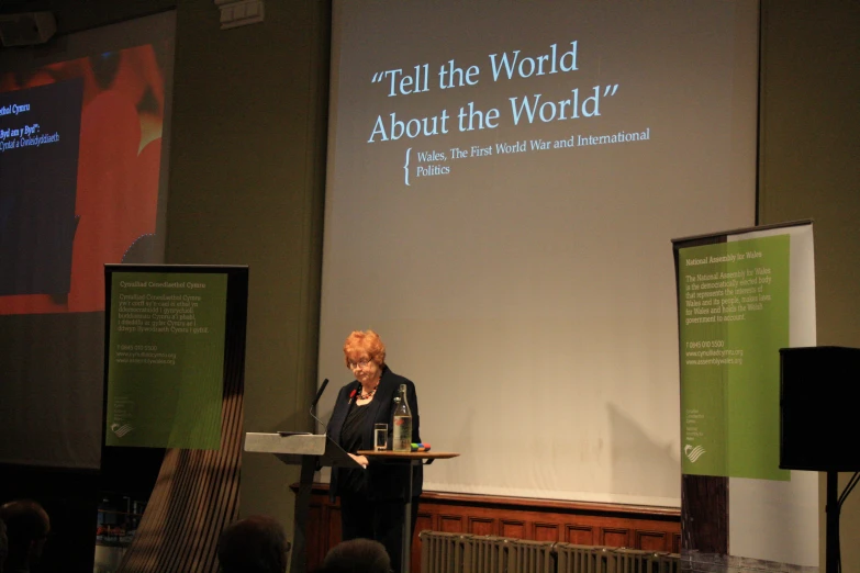 woman at podium speaking at panel presentation in dark room