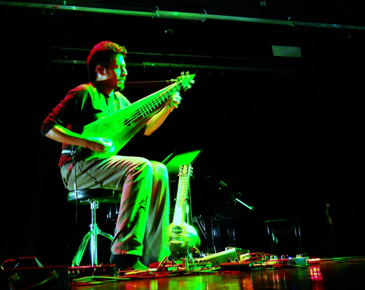 a man playing an electric guitar while sitting down