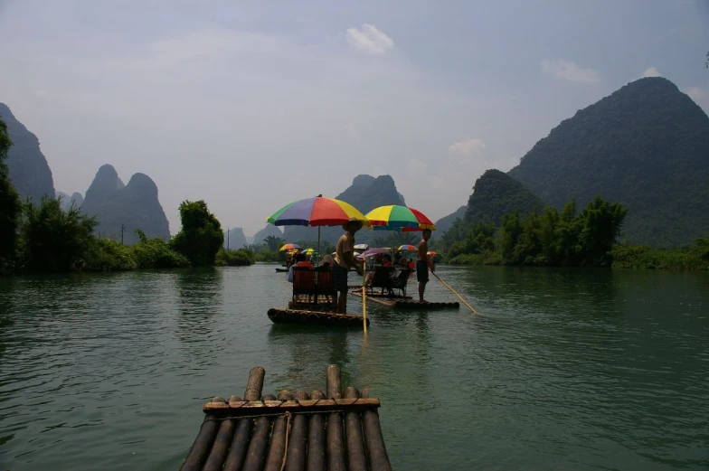 people riding small boats on the river in a mountainous area