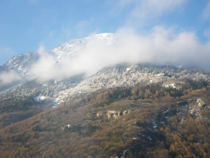 a snow covered mountain side with clouds on it