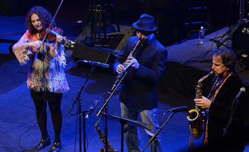 a man standing next to a woman while playing music on stage