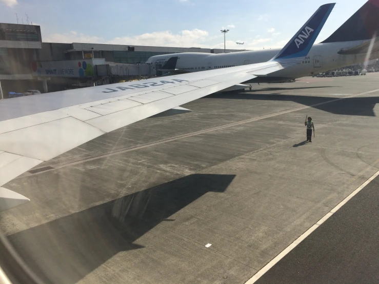 the side of an airplane with a person standing on a tarmac