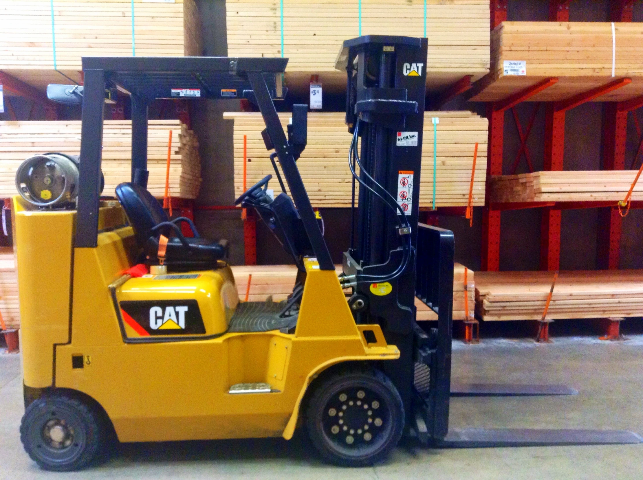 a yellow forklift in a warehouse filled with wooden pallets