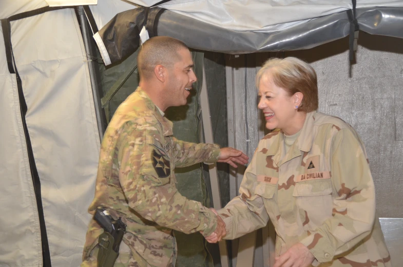 a soldier shakes the hand of a woman