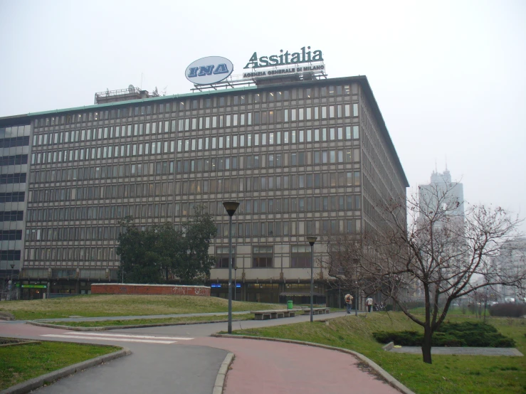 a brown building with a sign on top sitting in the center of a grassy area