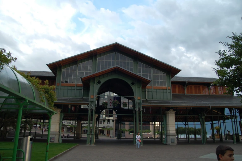 people outside the entrance of a large green building