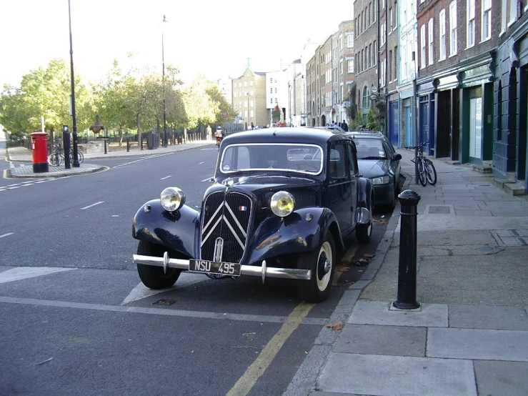 an antique car is parked in front of a parking meter