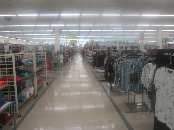 the interior of a clothing store with clothes in the aisle