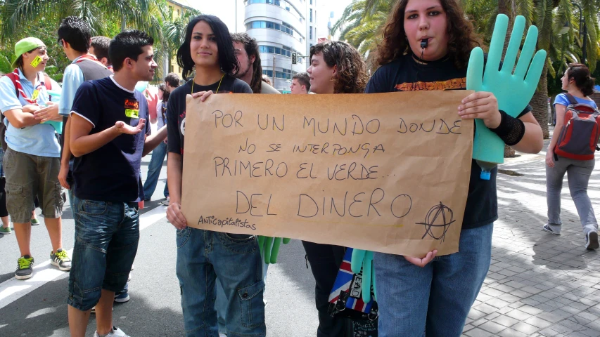 people holding a sign while walking down the street