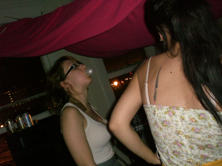 two girls in the middle of a party one singing a karaoke