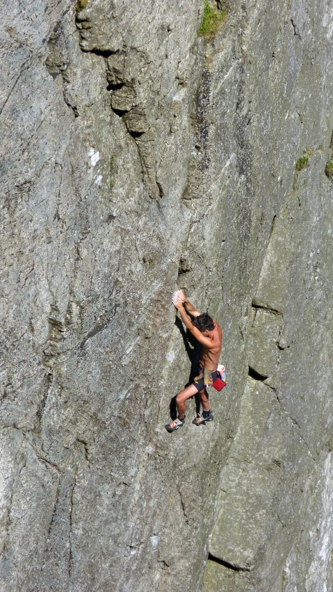 a shirtless man on a cliff face down