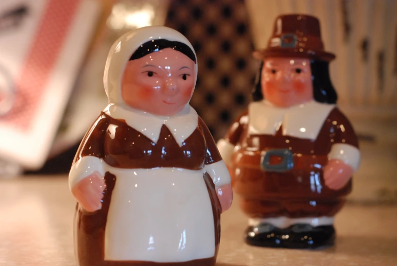 two small toy figurines, one wearing a brown and white outfit