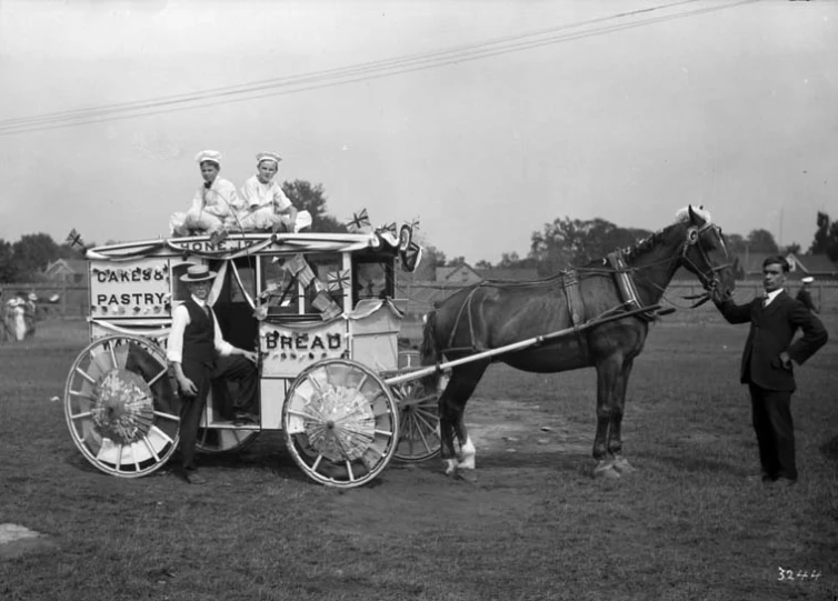 a horse drawn wagon with people standing on the back