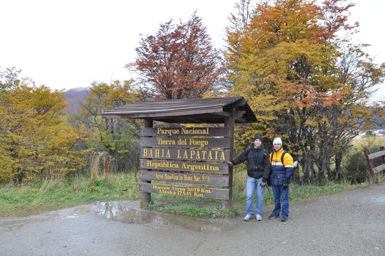 two people standing next to a forest sign