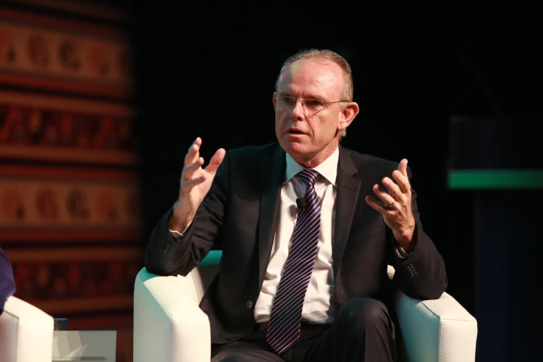 a man in glasses and tie sitting on a chair