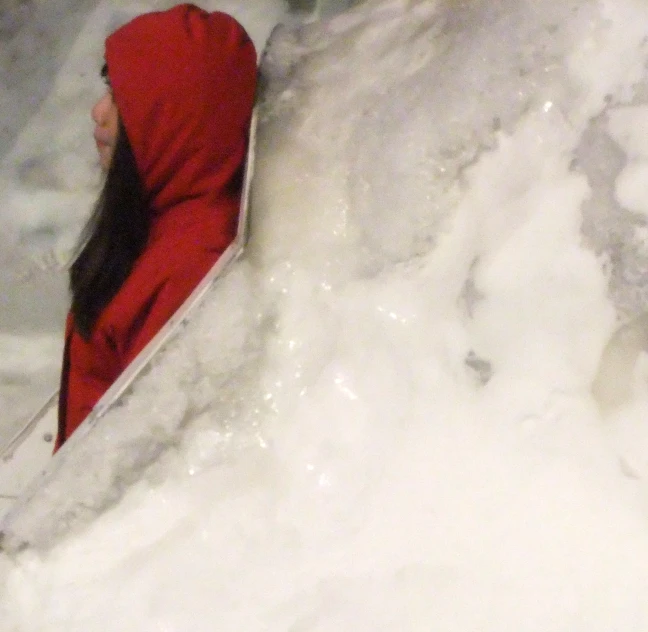 person in snowsuit with hooded jacket and red hat on